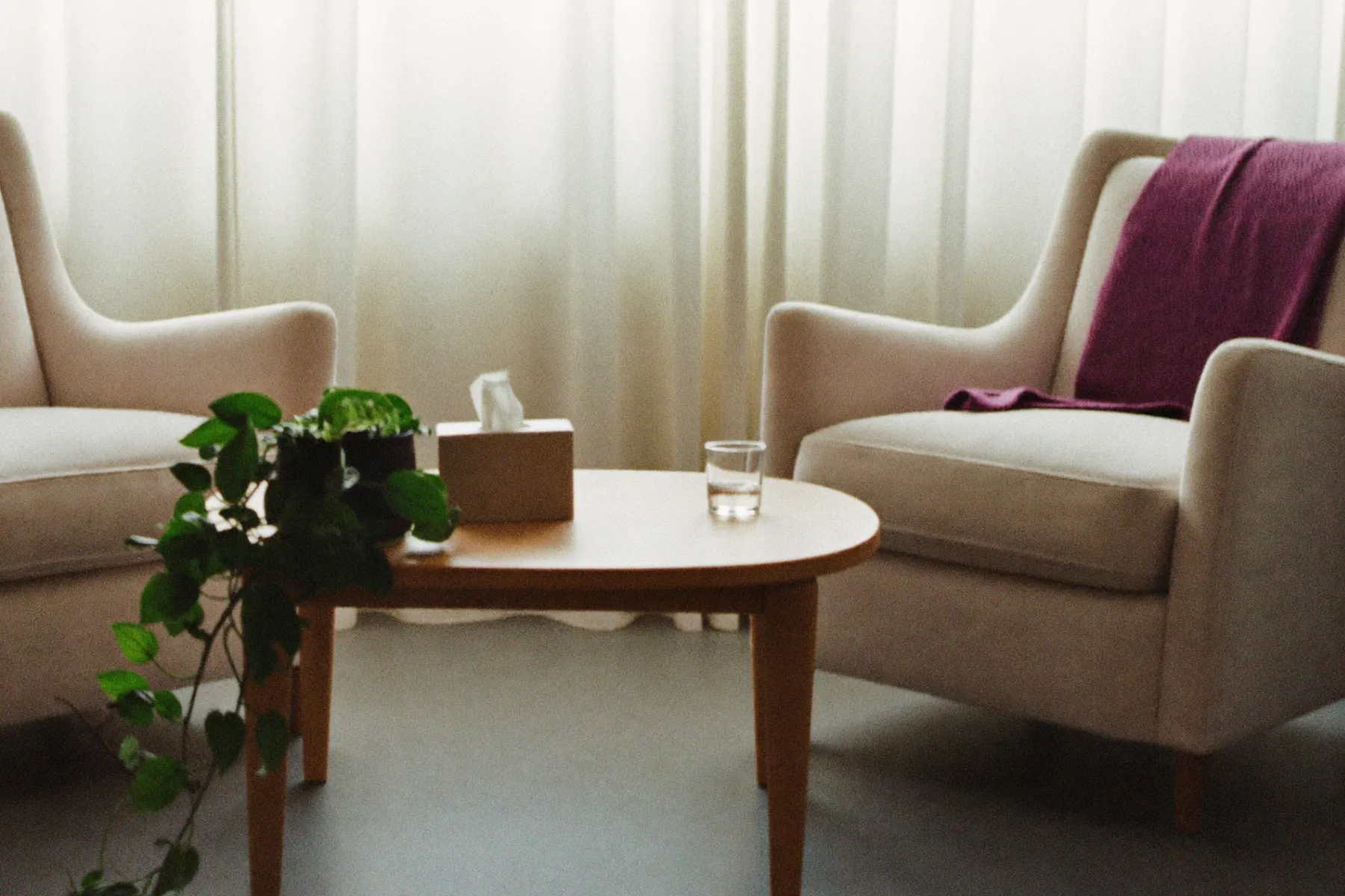 Two cream armchairs facing each other across a low table in a bright counselling room