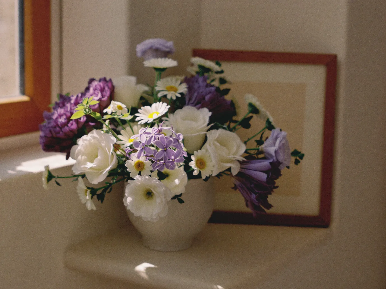 Fresh flowers in a vase on a sunlit windowsill