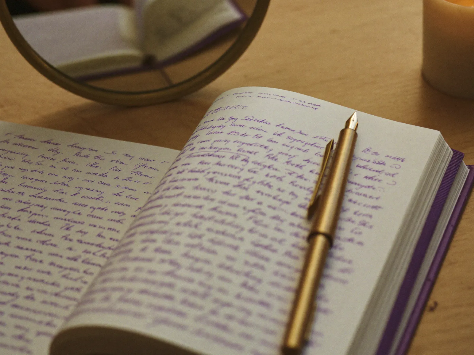 An open journal and pen beside a candle